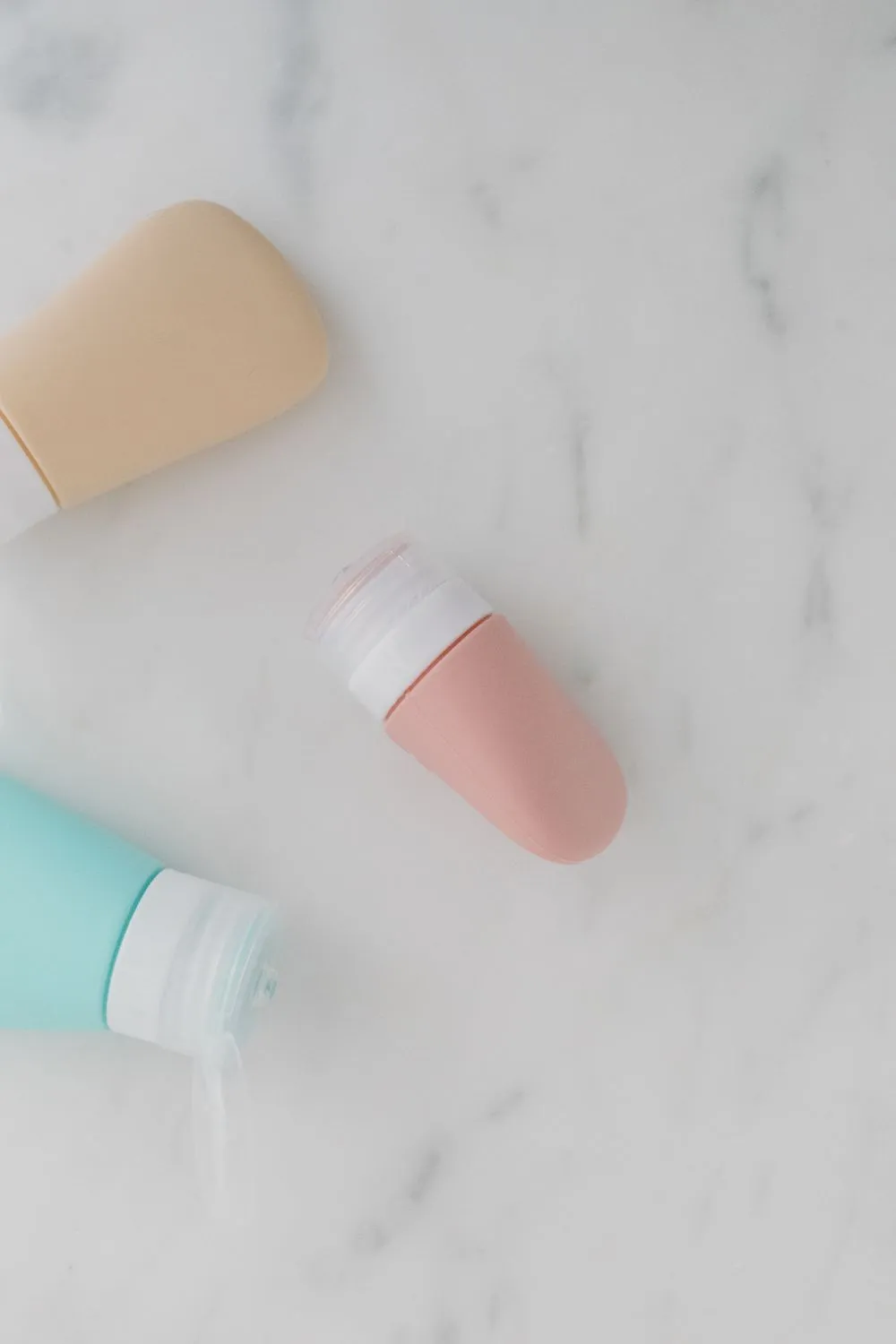 Hũ kem và chai dưỡng màu pastel trên mặt đá trắng