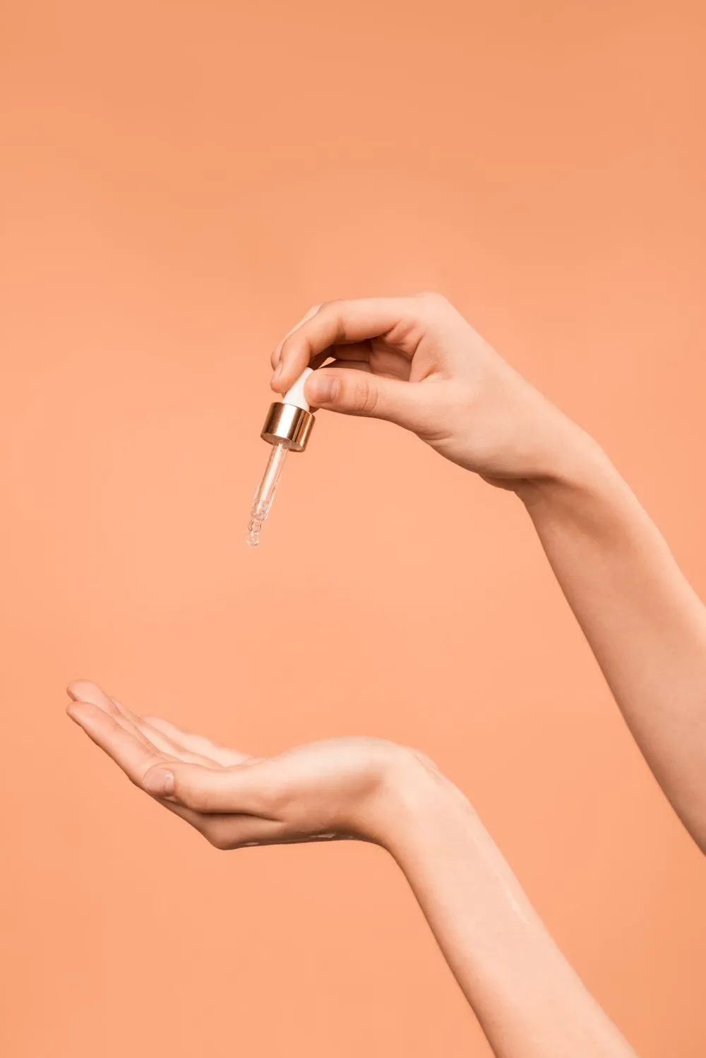 Nhỏ giọt serum xuống lòng bàn tay trên nền cam đào